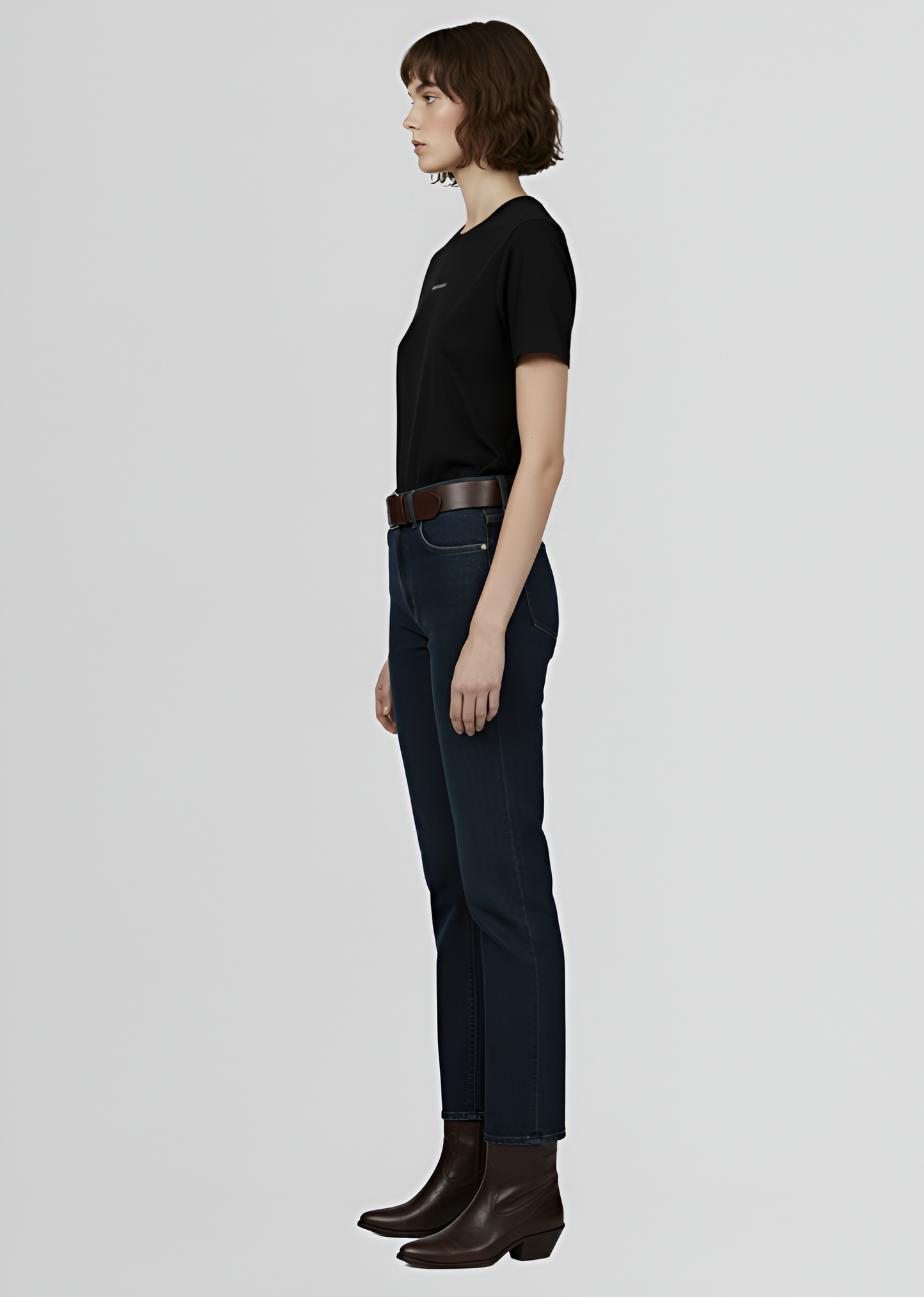 a woman wearing a black Northwind t-shirt, dark jeans, and brown boots on a light gray background