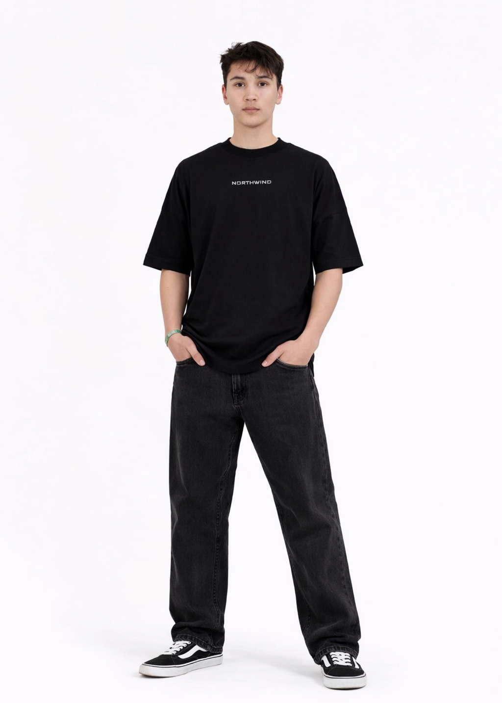 Young adult wearing a Northwind oversized organic cotton black t-shirt with Northwind embroidered on the chest, Carhartt pants, black Vans shoes