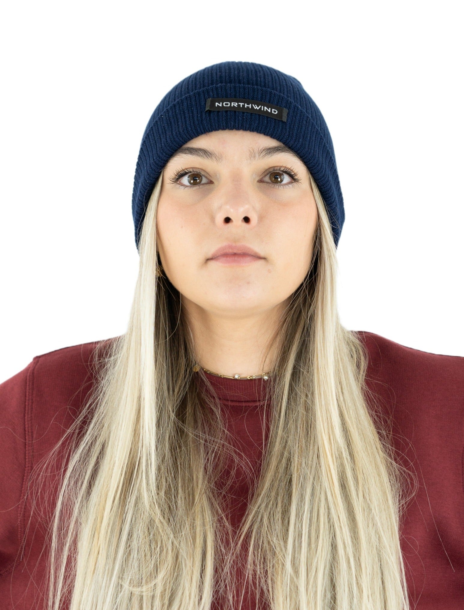 woman wearing a navy blue organic cotton beanie with a Northwind brand logo, and a Northwind organic cotton sweatshirt with embroidered logo on the chest