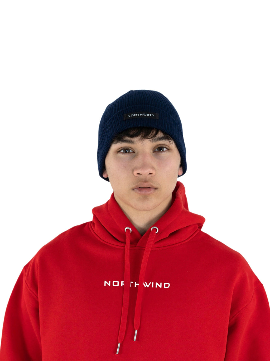Man wearing a navy blue organic cotton beanie with a Northwind logo, and a red organic cotton oversize heavy Northwind hoodie with embroidered logo on the chest