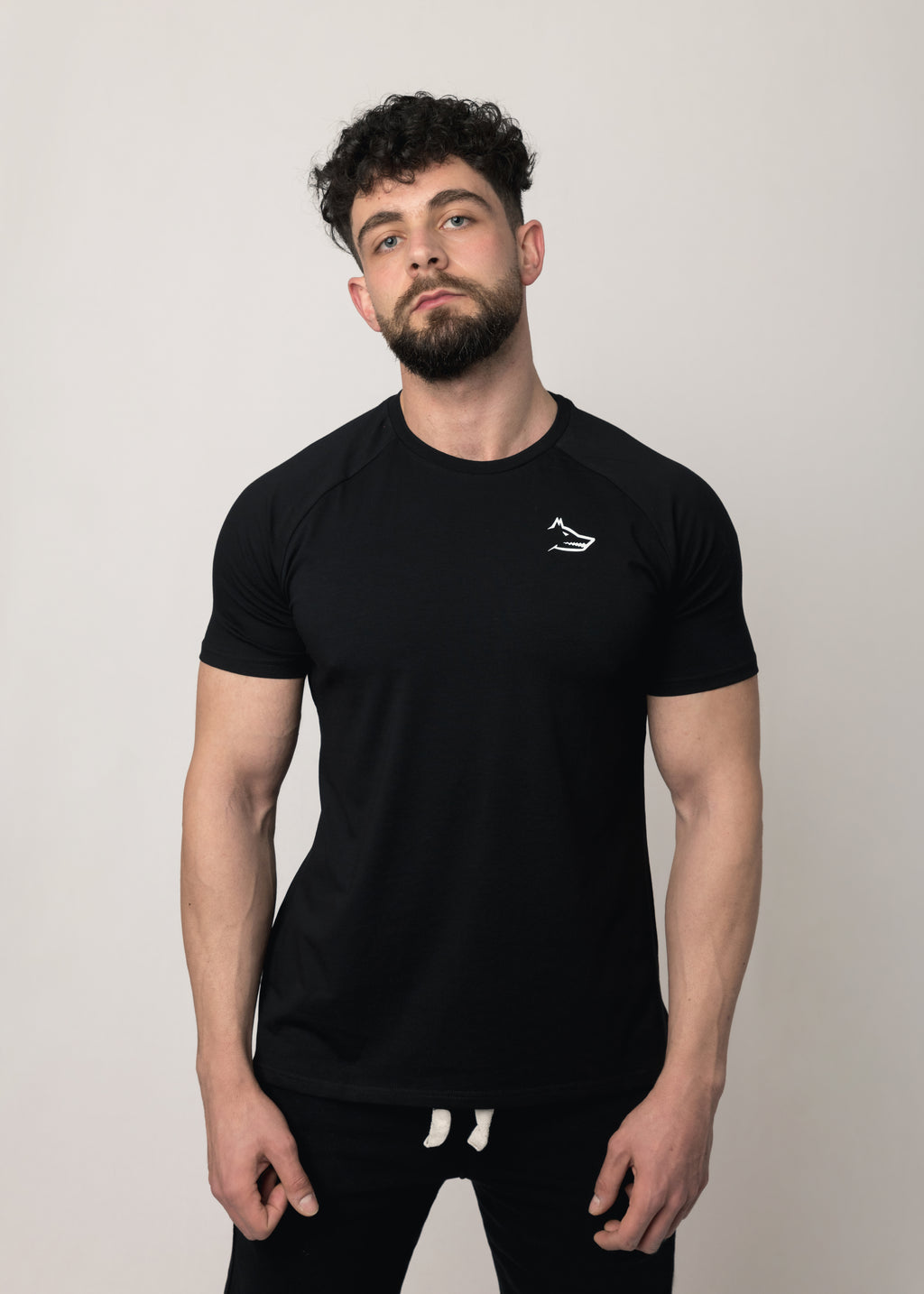 A male model wearing a black short-sleeved activewear t-shirt with a minimalist Northwind wolf logo on the chest.