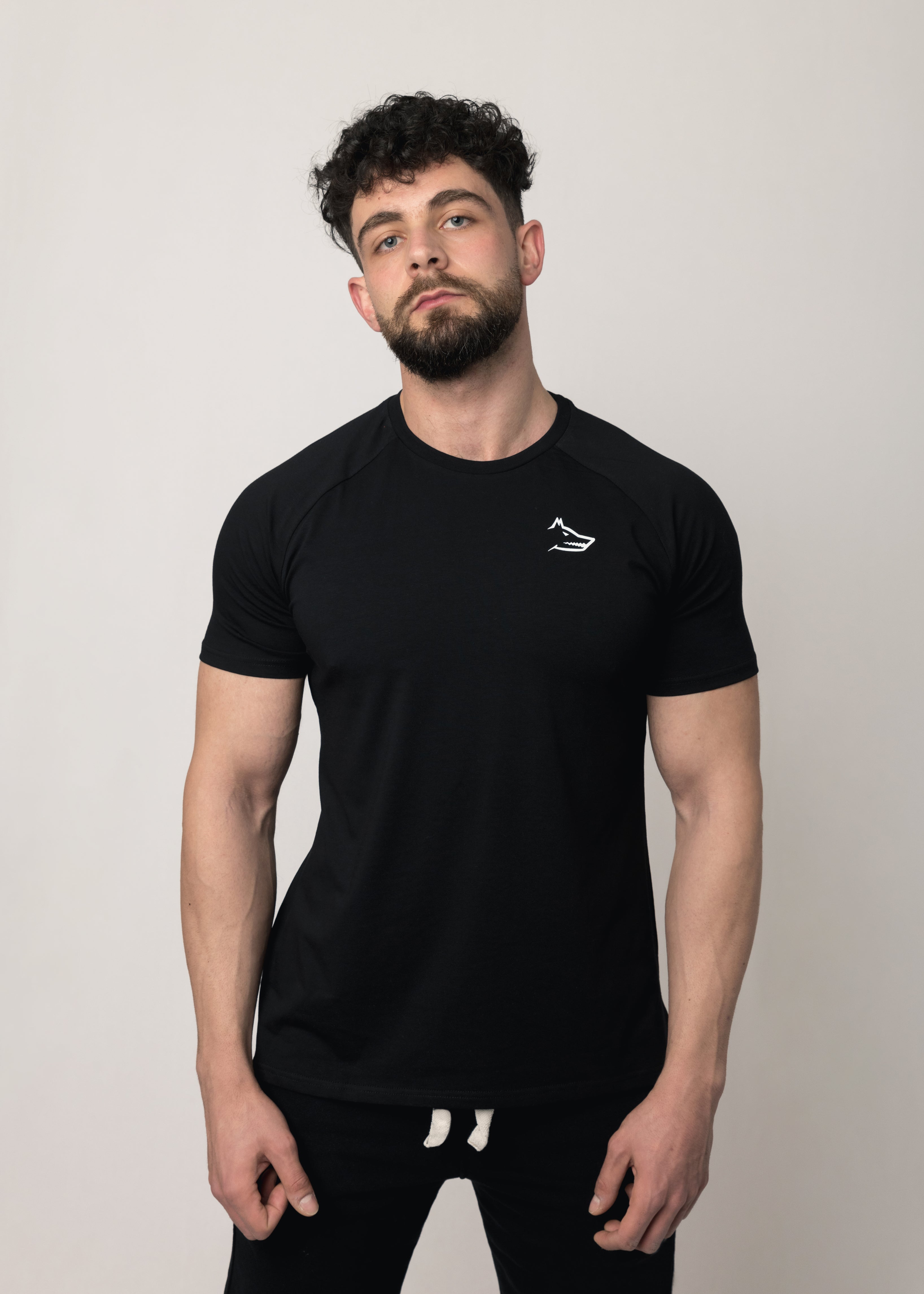 A male model wearing a black short-sleeved activewear t-shirt with a minimalist Northwind wolf logo on the chest.