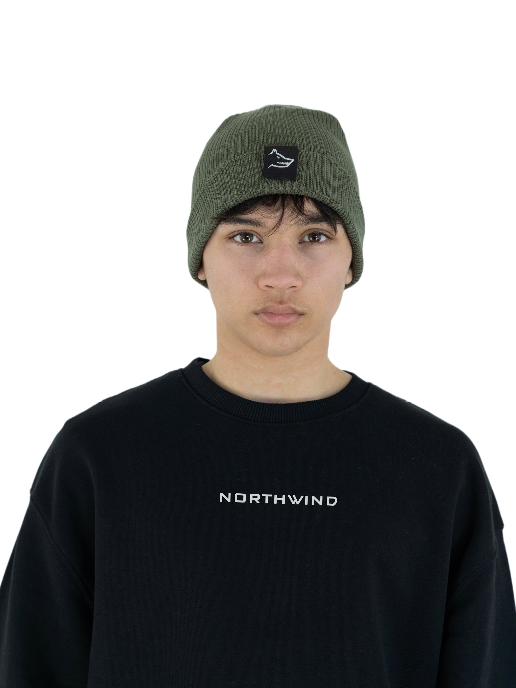 Man wearing a olive green organic cotton beanie with a Northwind wolf logo, and a black organic oversize Northwind sweatshirt with embroidered logo on the chest