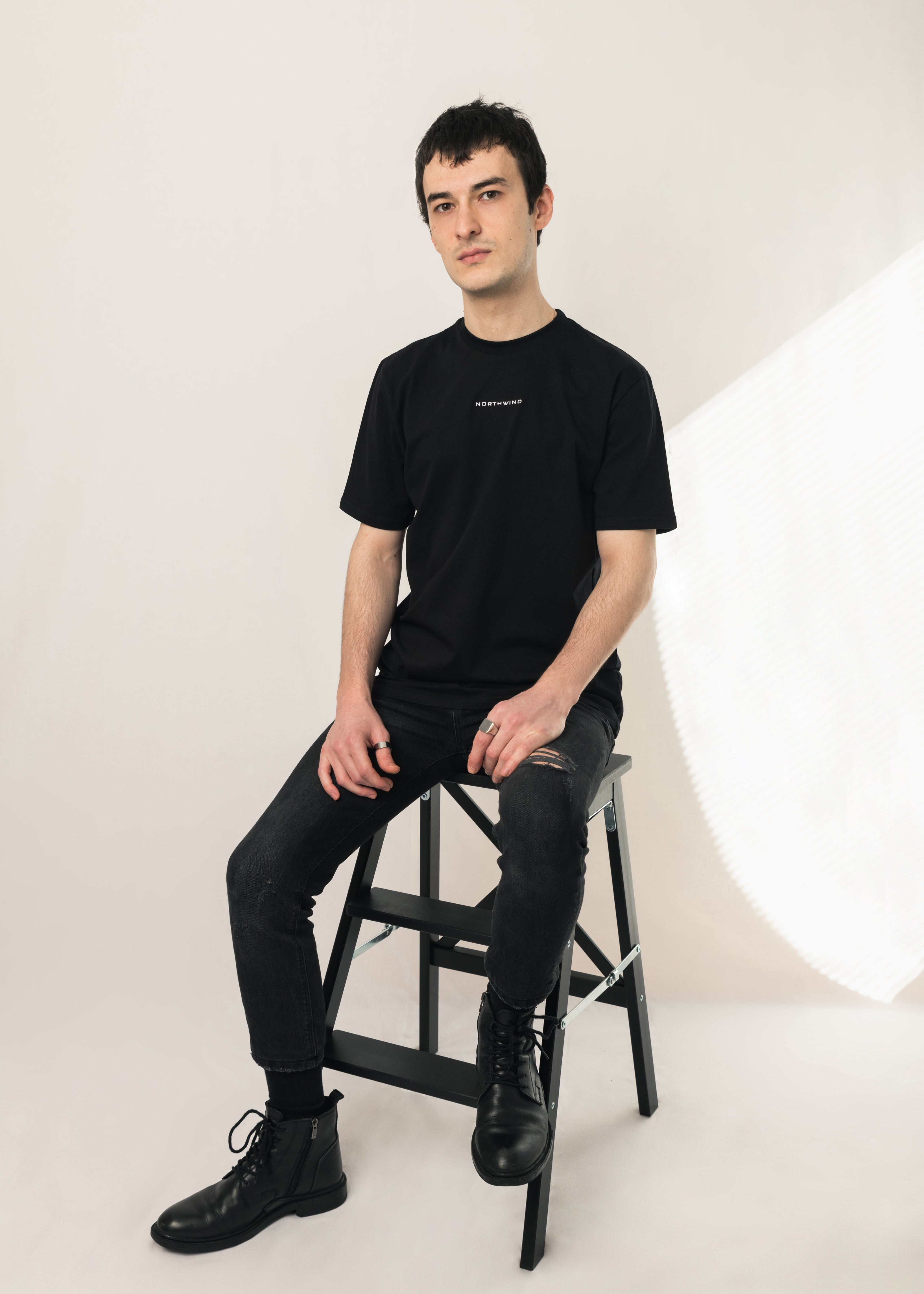 Paris Essential Black T-shirt by Northwind Antwerp and Paris with minimalist logo embroidery on the chair