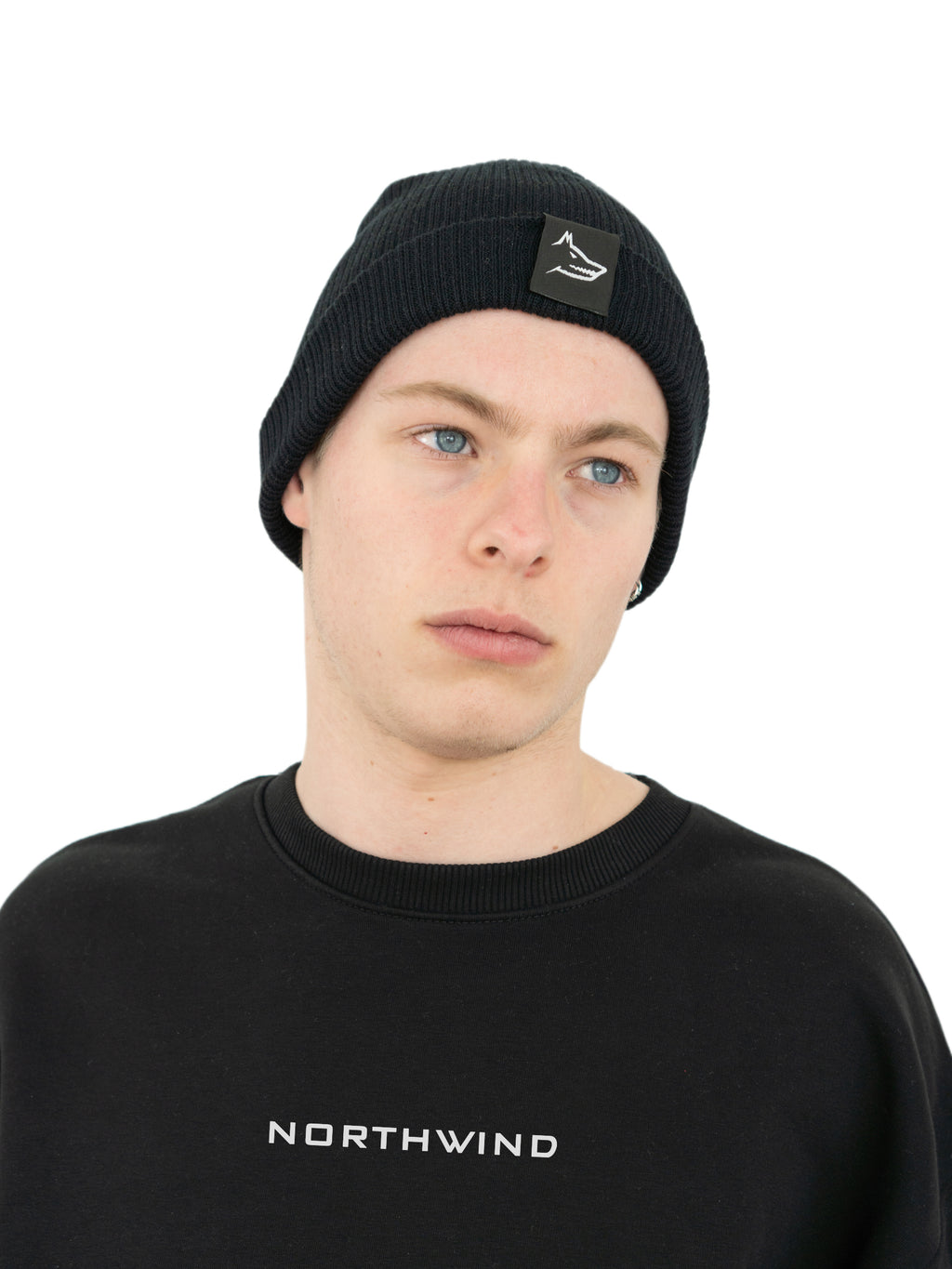 Man wearing a black organic cotton beanie with a Northwind wolf logo, and a black oversize heavy Northwind sweatshirt with embroidered logo on the chest
