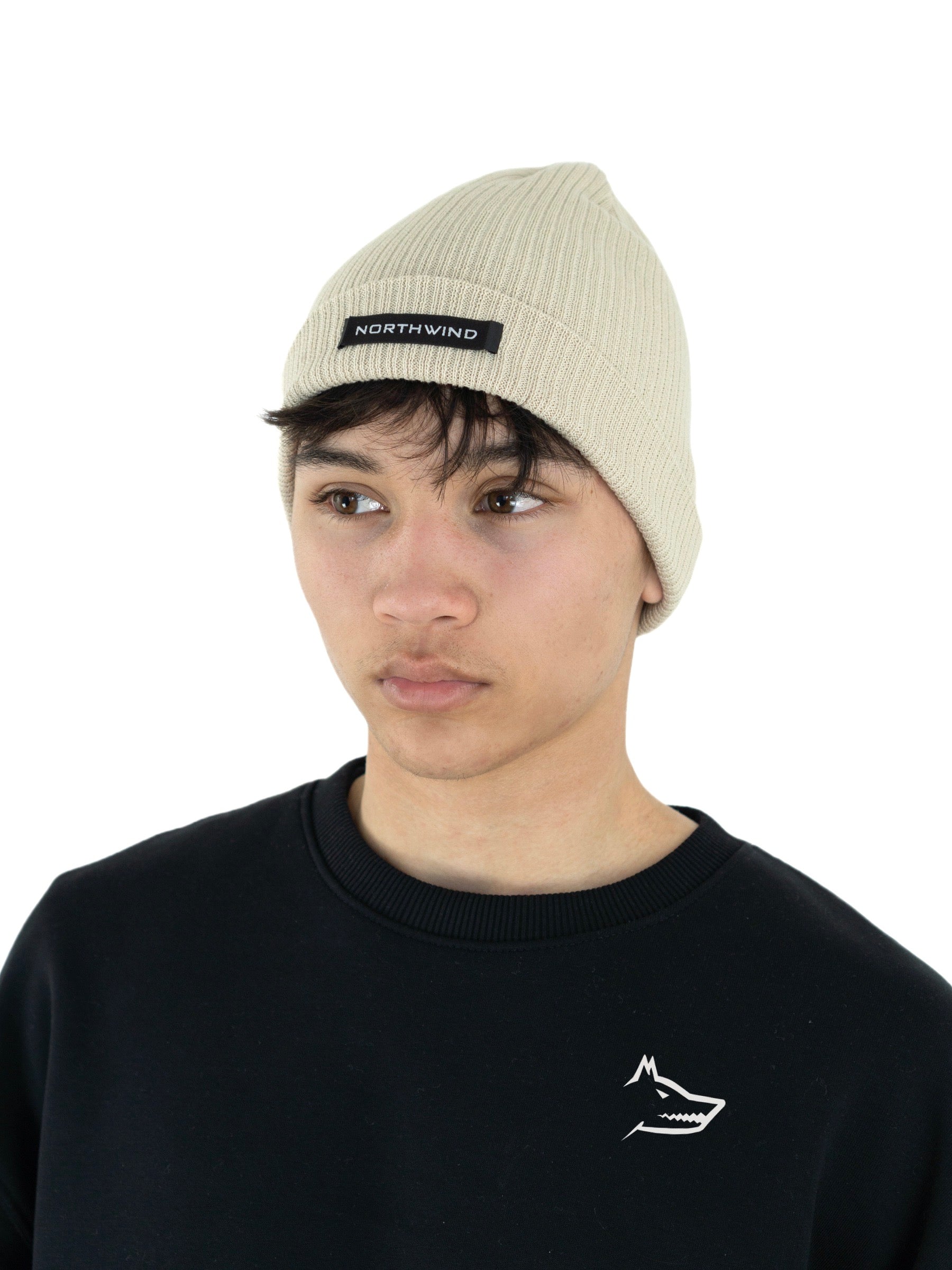 Man wearing a beige organic cotton beanie with a Northwind brand logo, and a black Northwind lone wolf sweatshirt with embroidered wolf logo on the chest