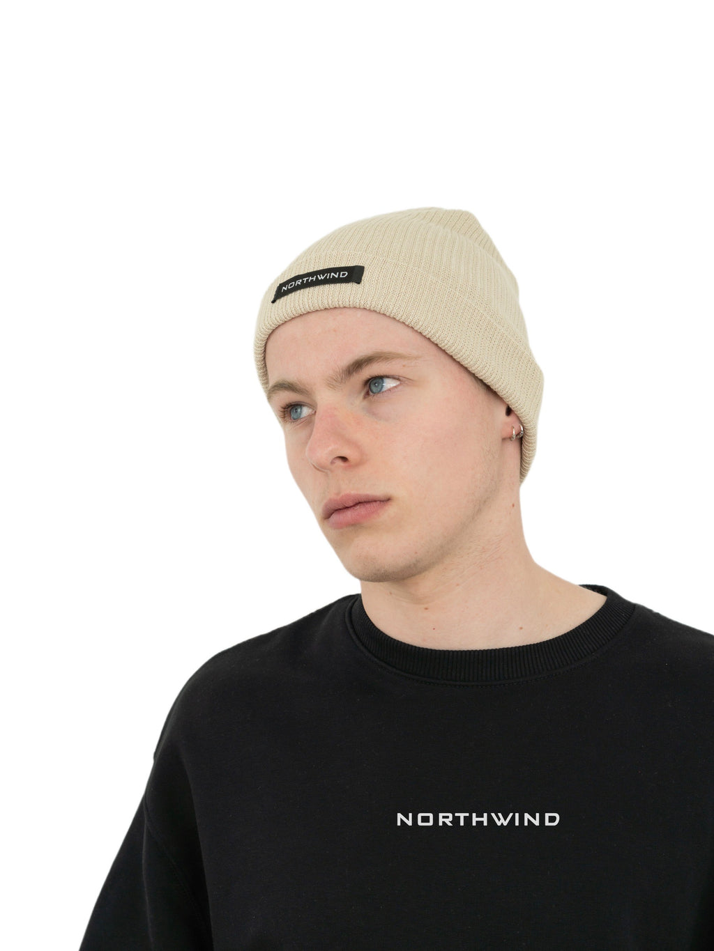 Man wearing a beige organic cotton beanie with a Northwind brand logo, and a black Northwind oversize organic cotton sweatshirt with Northwind logo on the chest