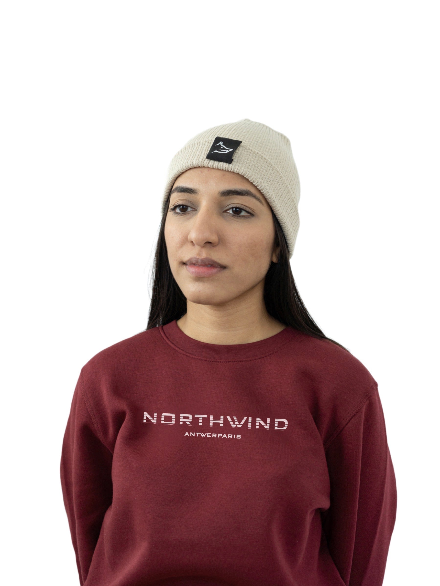woman wearing a beige organic cotton beanie with a Northwind wolf logo, and a Northwind organic cotton sweatshirt with Northwind logo on the chest