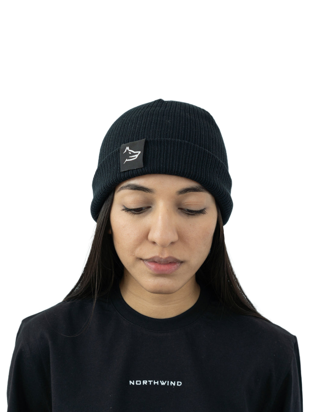 woman wearing a black organic cotton beanie with a Northwind wolf logo, and a Northwind casual t-shirt with embroidered Northwind logo on the chest