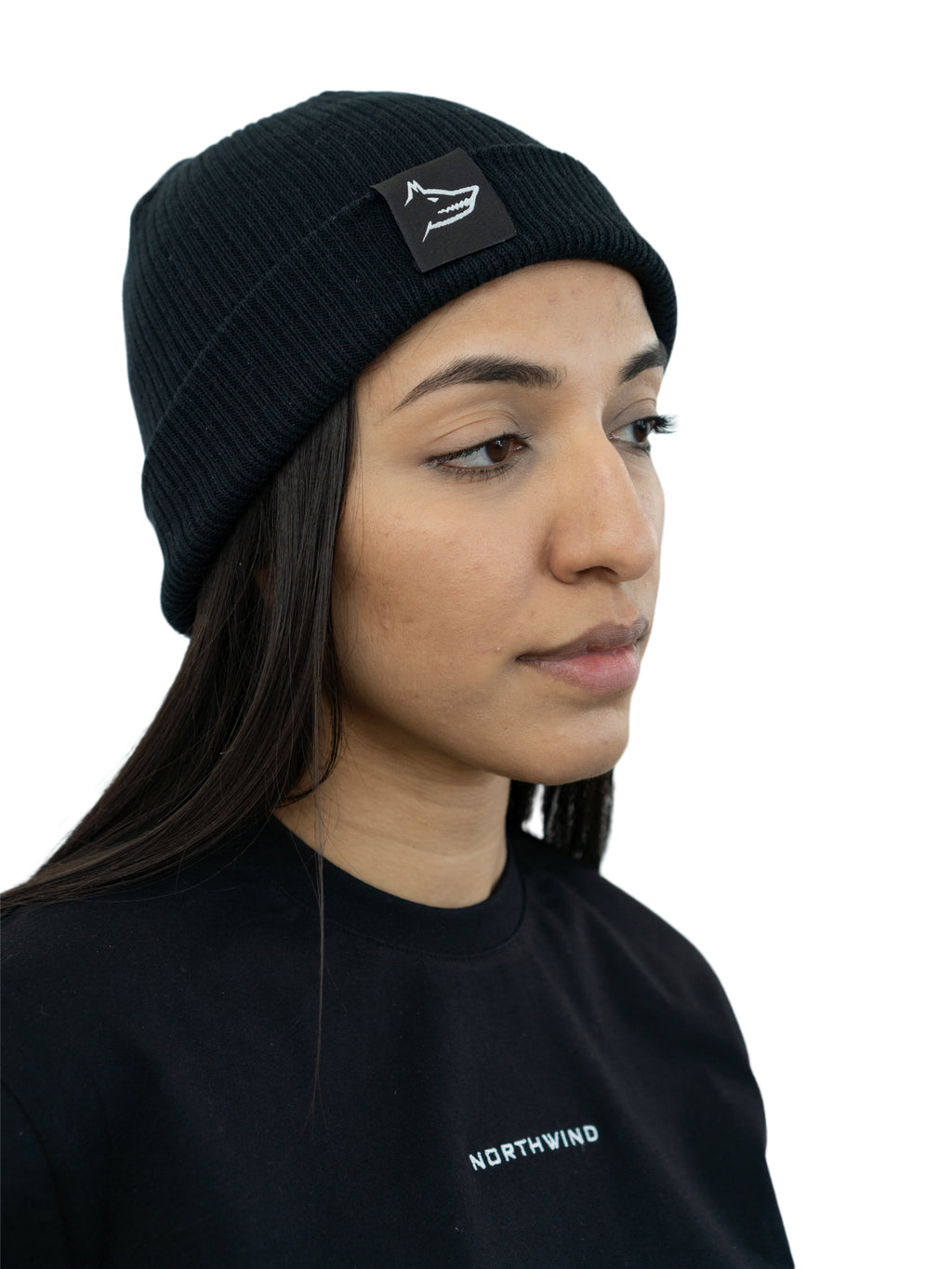 woman wearing a black organic cotton beanie with a Northwind wolf logo, and a Northwind casual t-shirt with embroidered Northwind logo on the chest